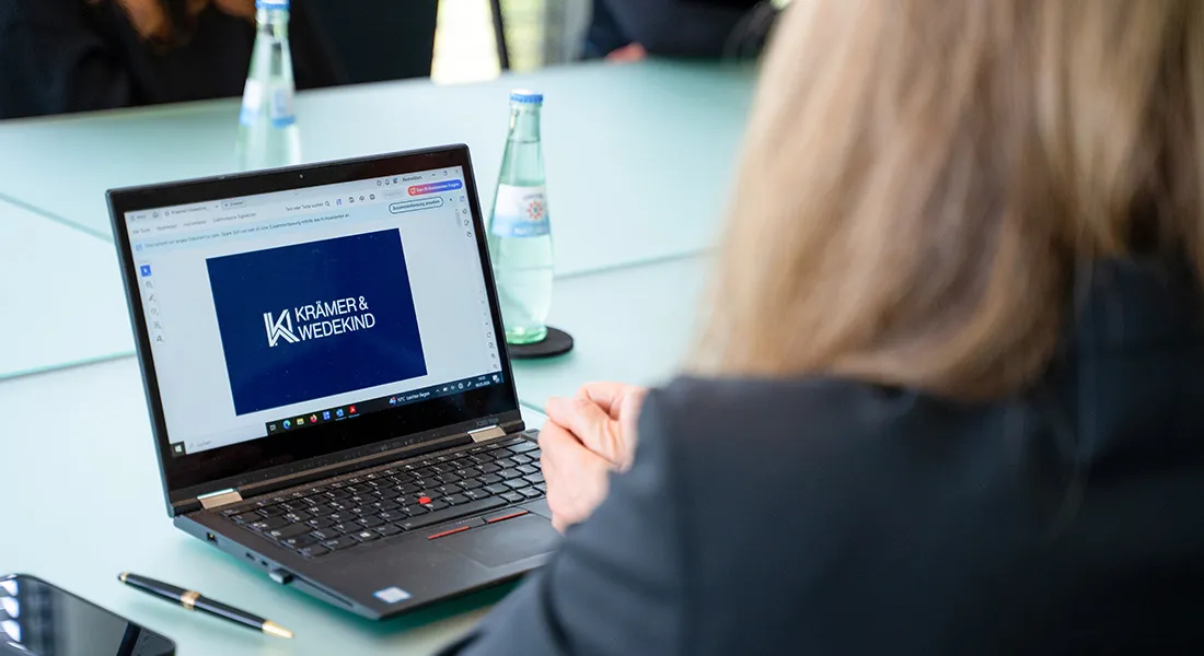 Drei Kollegen besprechen gemeinsam Inhalte auf einem Tablet in einem hellen, modernen Büro.